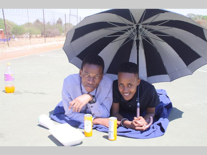 Serari Matlhagari and Matsmatsi Mametja celebrate their 40 days at the achool under an umbrella with snacks and drinks.