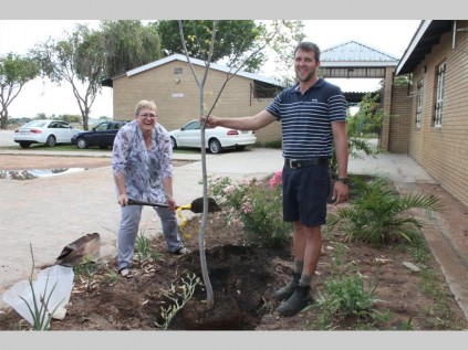 Hugo van Zyl  (Rentsini Kwekery, bestuurder) hy help vir Hellen Peasall (departement van onderwys,waarnemende kringbestuurder om een van die 30 bome wat Rentsini Kwekery aan Westenburg Sekondêre Skool geskenk het, te plant in die skool se tuin.