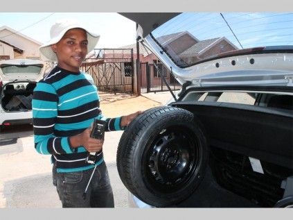 Vivian Buys removes the spare wheel and car jack from the vehicle's boot.