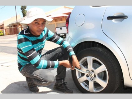Vivian Buys loosens the wheel nuts before jacking up the vehicle to remove the flat tyre.