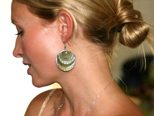 Tanya Koch shows off a pair of earrings she made from bottle caps and framed art work from bottle caps. Making something from bottle caps only needs imagination, says Tanya Koch.