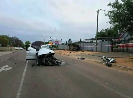 A close-up of an early morning crash scene showing a badly damaged vehicle in the middle of a road. 