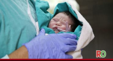 A doctor holds a newborn baby.