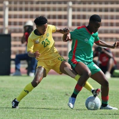 Two footballers jostling for the ball.