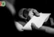 A man hands an envelope to another man.