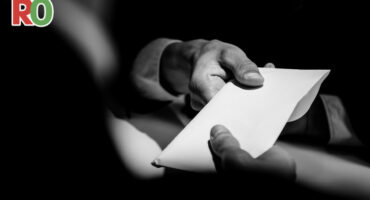 A man hands an envelope to another man.