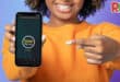 A girl points at a phone with a loading screen to a website.