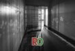 prison interior, two parallel walls joing with a jail grille, black and white image with some light shining in