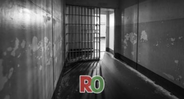 prison interior, two parallel walls joing with a jail grille, black and white image with some light shining in
