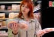 A woman choosing between two similar products in a grocery store.