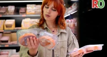 A woman choosing between two similar products in a grocery store.