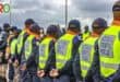 Traffic police stand in a line with their backs to the camera.