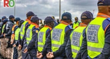 Traffic police stand in a line with their backs to the camera.