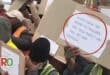 Residents during a protest hold up boards that read "What have we done to deserve this treatment, we are enough".