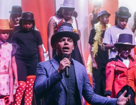 Shaun Hansel leads the performers in song.
