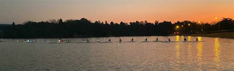 Paddlers on the water as the sun sets over Dabulamanzi Canoe Club.