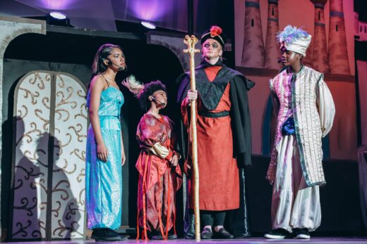 The cast of Aladdin acts a scene out on stage.