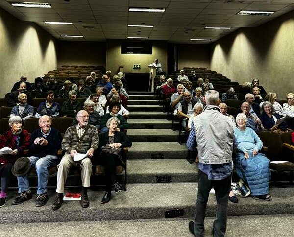 The audience awaits the screening of the documentary.