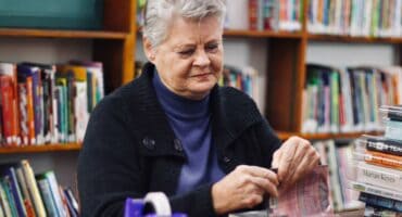 Maureen Freeman places Sellotape on books as she covers them on July 7, 2026, at the Linden Library. Photo: Neo Phashe