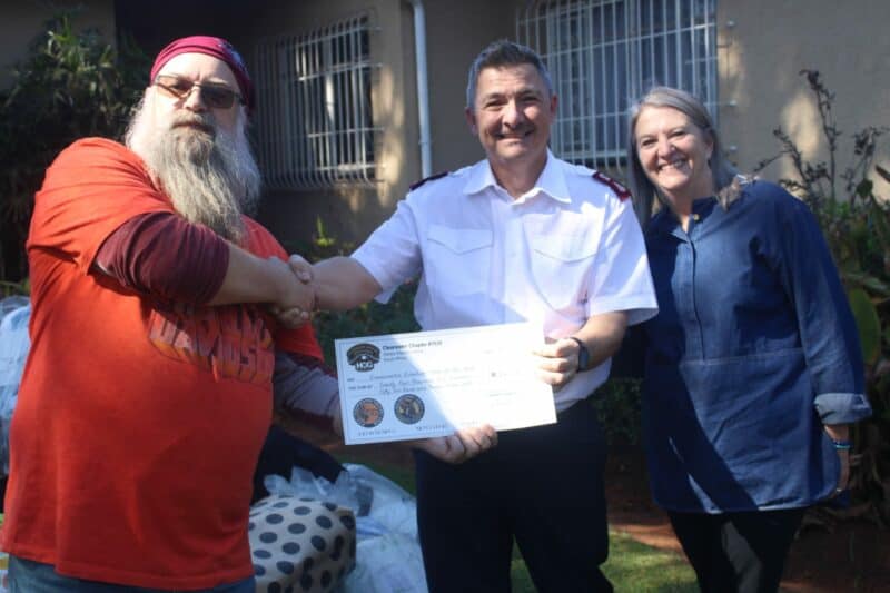 Cornell Grewar (left) and Sonja Hood (right) of Clearwater Chapter South Africa Harley Owners Group present a donation cheque to Darren Huke (middle) of Eventide Home for the Aged on July 18, 2026, in Emmarentia. Photo: Waydon Jacobs