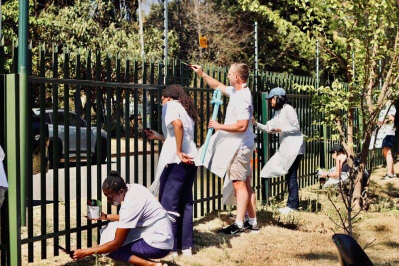 Community members happily paint the fence. Photo: Neo Phashe