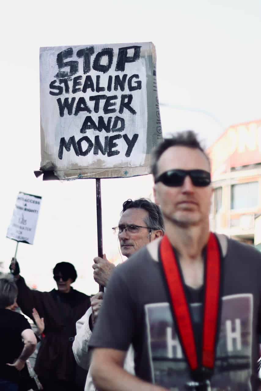 A protester holds up a board that reads, ‘Stop stealing water and money’, on September 14, 2026, in Melville. Photo: Neo Phashe