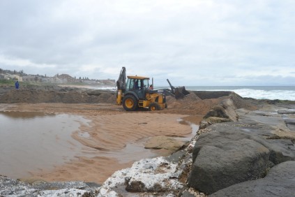 Lifeguards look on as the loader has plenty of work to do.