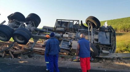 Workers look at the over turned truck on the N2.