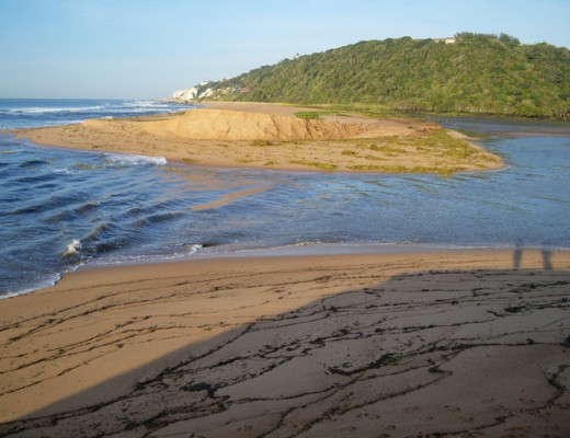 The massive breached area is wide open, allowing the tidal water to flow into the estuary.
