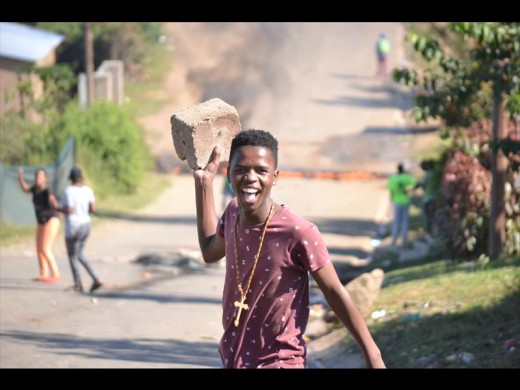 One of the young protesters in Shayamoya carrying a brick that was used to block the road.