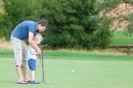 20680314 - young handsome father teaching his little son how to play golf stock