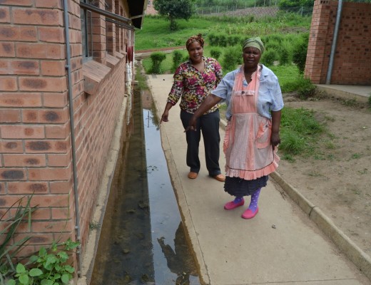 Parents Bible Nthembu and Golide Khweshube point out mosquito-infested pools of water around the school.