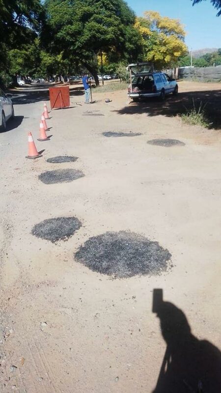Member of the AfriForum pothole project filling up a pothole.