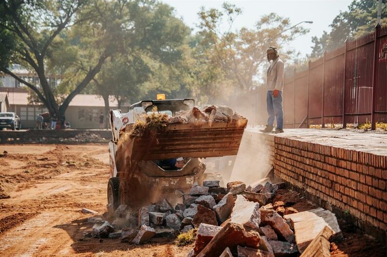 A man is working on a brick wall with a bulldozer.