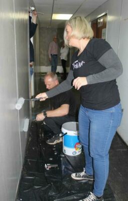 Kotie Davies and Dean Clark paint one of the police station walls.