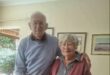 Elderly couple smiling, celebrating 60 years of marriage in their home.