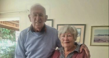 Elderly couple smiling, celebrating 60 years of marriage in their home.