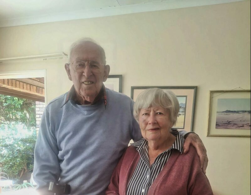 Elderly couple smiling, celebrating 60 years of marriage in their home.