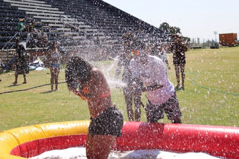Students get soaked by water spraying over an inflatable paddling pool during outdoor games at the spring day event. Photo: Nkazimulo Ncube