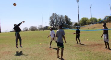 A group of students play volleyball on the grass at the Randburg Sports Complex, with inflatable attractions visible in the background. Photo: Nkazimulo Ncube