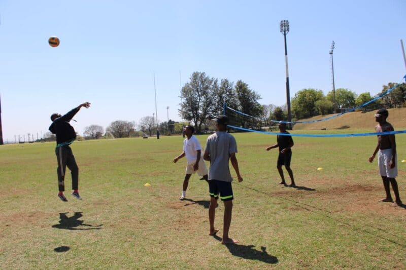 A group of students play volleyball on the grass at the Randburg Sports Complex, with inflatable attractions visible in the background. Photo: Nkazimulo Ncube