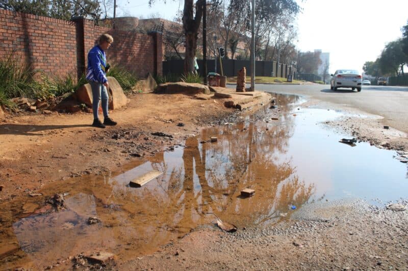 Ward 102 councillor Bea Campbell-Cloete at the troubling leak on Pretoria Road in Ferndale. Photo: Mthulisi Lwazi Khubon