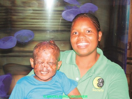 Me. Fisanie Mahlangu (maatskaplike werker van Middelburg) met klein Mnqobi Mthembu op haar skoot.