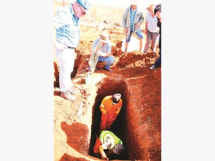 Mnre. Frans Mahlangu (assistent argeoloog) en Josiah Mhlangu besig om die oorskot versigtig uit te grawe terwyl die familie toekyk. Frans het meer as 20 jaar ondervinding as grafopgrawer.