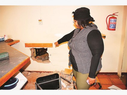 Me. Khethiwe Stockie wys na die gat in die muur wat inbrekers vanaf dr. Alexis Mashifane se spreekkamer gemaak het om by die weddenskap agentskap, BET SA, se instapkluis uit te kom.