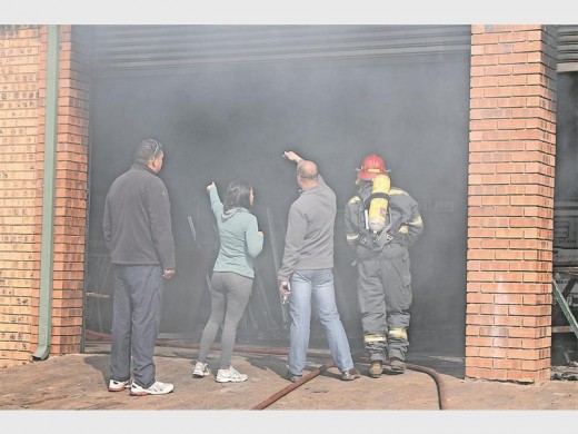 Van die mense op die toneel wys brandweermanne waar artikels nog smeul en rook veroorsaak na die brand.