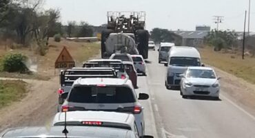 Traffic jam on a rural road with several cars and a large truck. Vehicles are stopped behind the truck, suggesting a slower pace and congestion.