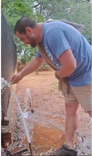 Man brushes his teeth at fountain of broken water meter.