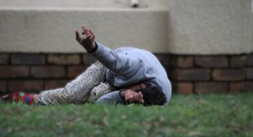 A drug addict crawling around on the grass.