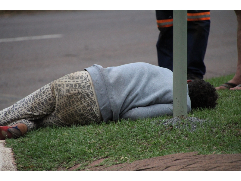 Drug addict lying on his side on the pavement.